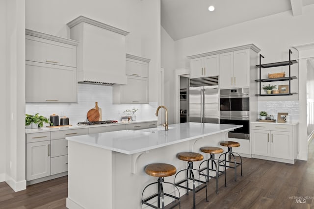 kitchen with appliances with stainless steel finishes, sink, a kitchen island with sink, a breakfast bar, and decorative backsplash