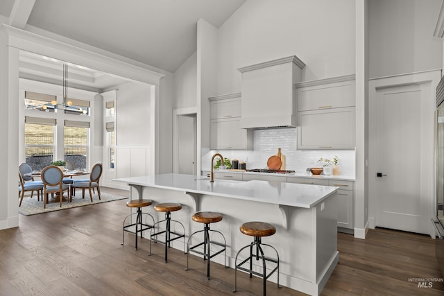 kitchen with a notable chandelier, an island with sink, a breakfast bar area, and backsplash