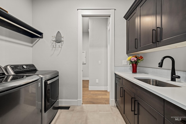 laundry room featuring washer and dryer, sink, light tile patterned floors, and cabinets