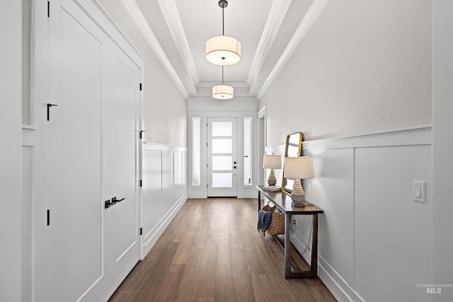 doorway with dark wood-type flooring, crown molding, and a raised ceiling