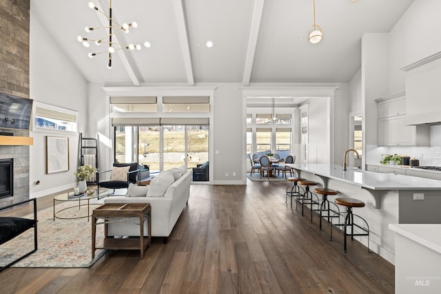 living room featuring high vaulted ceiling, an inviting chandelier, beamed ceiling, and a fireplace