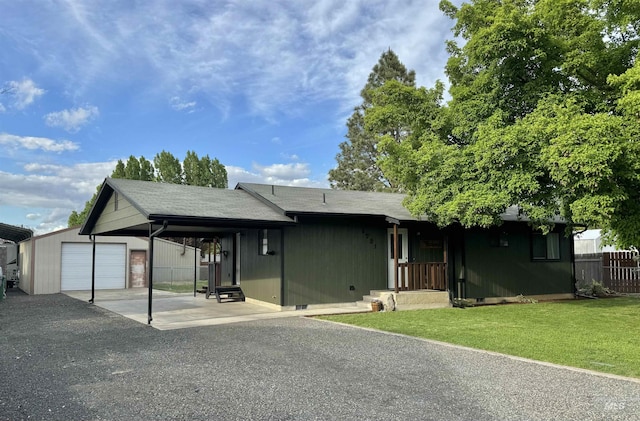 ranch-style house featuring fence, a shingled roof, a front lawn, an outdoor structure, and gravel driveway