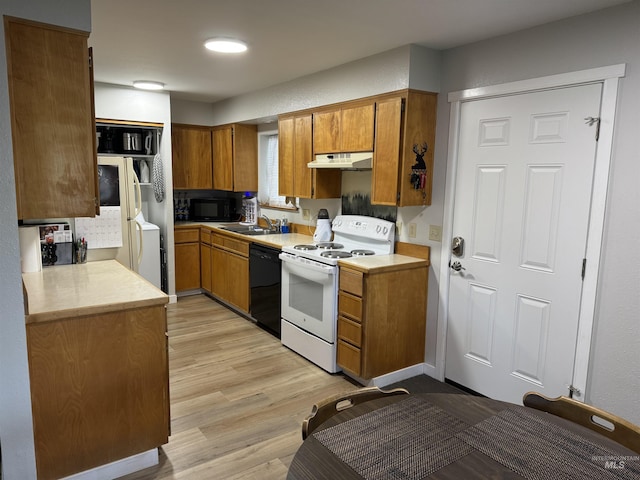 kitchen featuring brown cabinets, light countertops, light wood-style flooring, under cabinet range hood, and black appliances