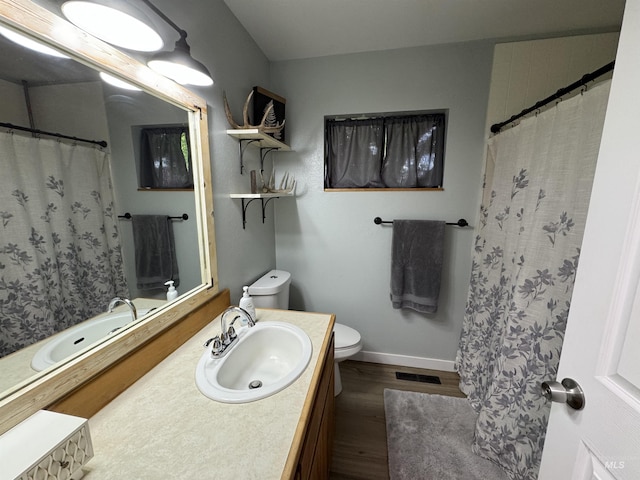 bathroom with visible vents, vanity, wood finished floors, toilet, and baseboards