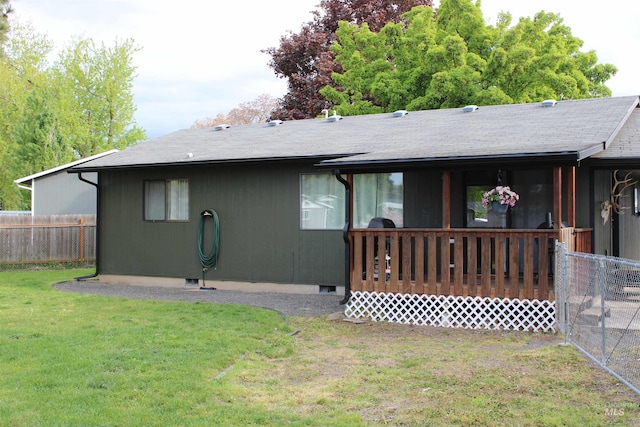 back of house with roof with shingles, fence, and a yard