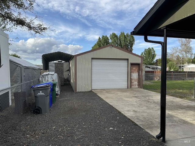 detached garage featuring fence and driveway