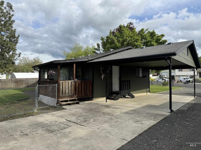 view of front of property featuring concrete driveway, fence, and an attached carport