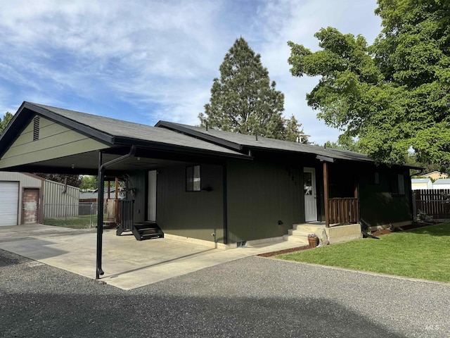 view of front of home with a front lawn, fence, entry steps, an outbuilding, and a carport