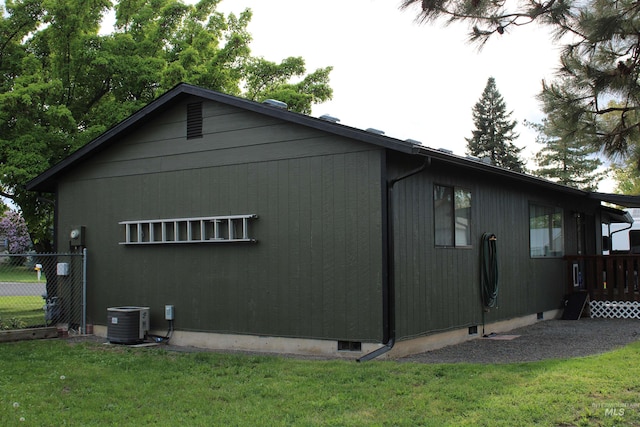 view of home's exterior featuring a lawn, central AC, and fence