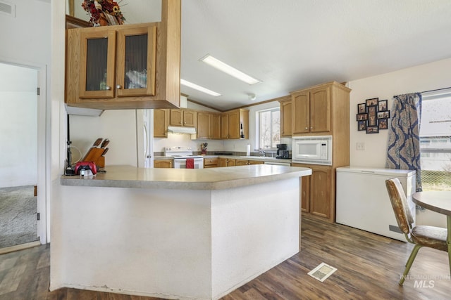 kitchen with sink, white appliances, dark wood-type flooring, vaulted ceiling, and kitchen peninsula