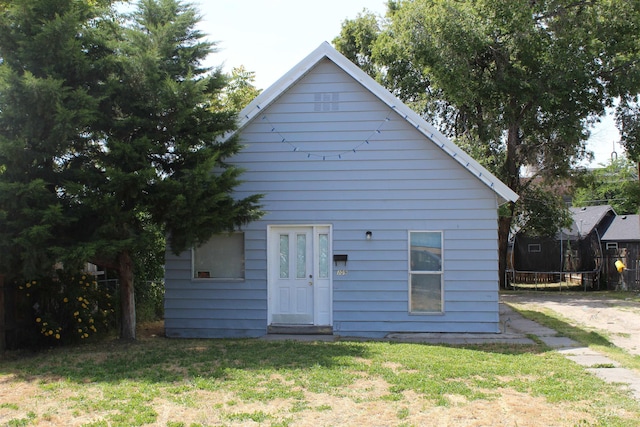 rear view of property featuring a trampoline and a lawn