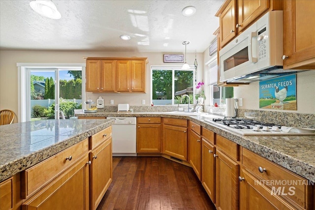 kitchen with white appliances, tile counters, dark wood-style flooring, pendant lighting, and a sink