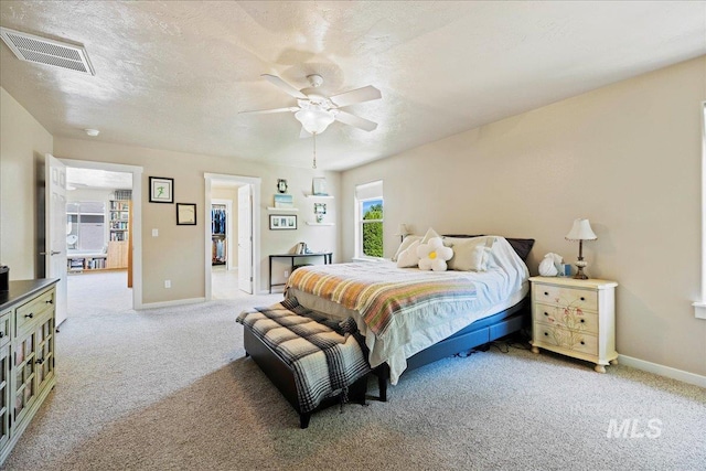 bedroom featuring light colored carpet, visible vents, a textured ceiling, and baseboards