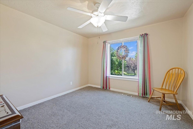 living area with carpet, a textured ceiling, baseboards, and a ceiling fan