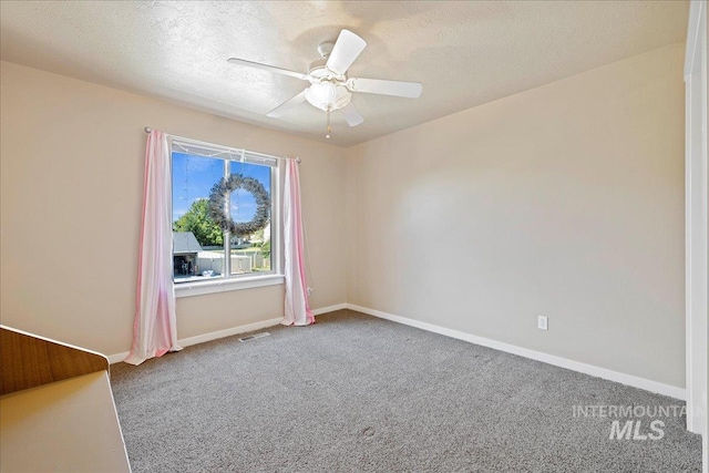 spare room featuring a ceiling fan, carpet, baseboards, and a textured ceiling