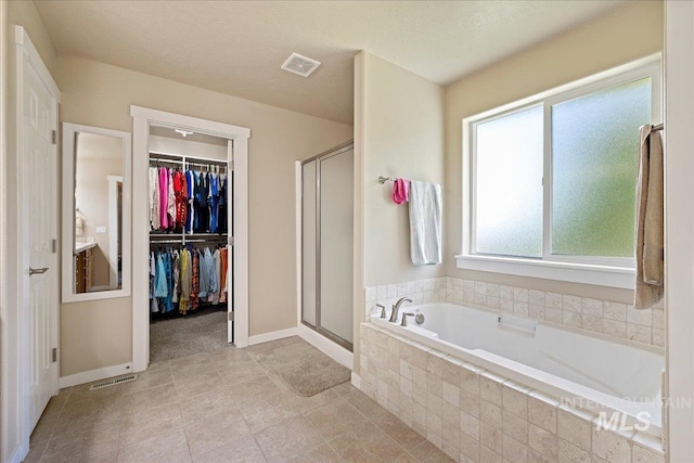 full bath with a stall shower, visible vents, a spacious closet, and a bath