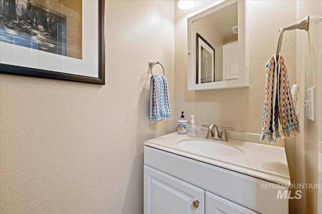 bathroom with a textured wall and vanity