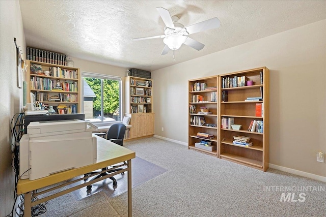 carpeted office space featuring a textured ceiling, a ceiling fan, and baseboards