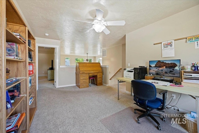 carpeted office featuring visible vents, a textured ceiling, and baseboards