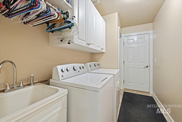 laundry room with cabinet space, baseboards, independent washer and dryer, a textured ceiling, and a sink