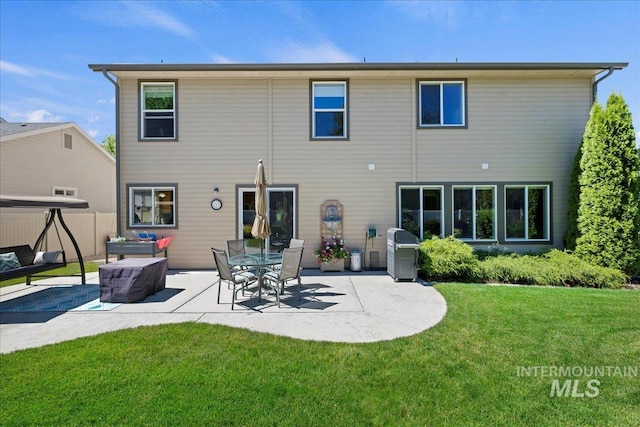 rear view of house featuring a yard, fence, and a patio