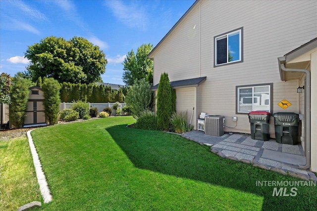 view of yard with an outbuilding, central AC unit, fence, a shed, and a patio area