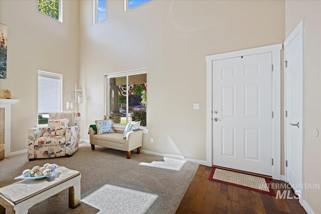 living room featuring a high ceiling, a tiled fireplace, wood finished floors, and baseboards