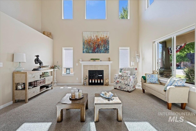 carpeted living area featuring a fireplace, a towering ceiling, and baseboards