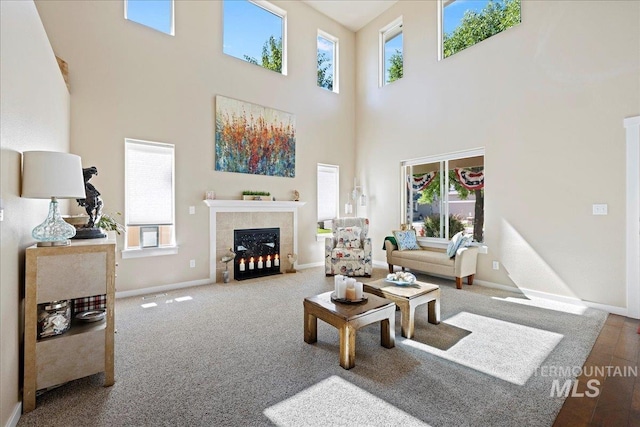 living room with a high ceiling, a tiled fireplace, and baseboards