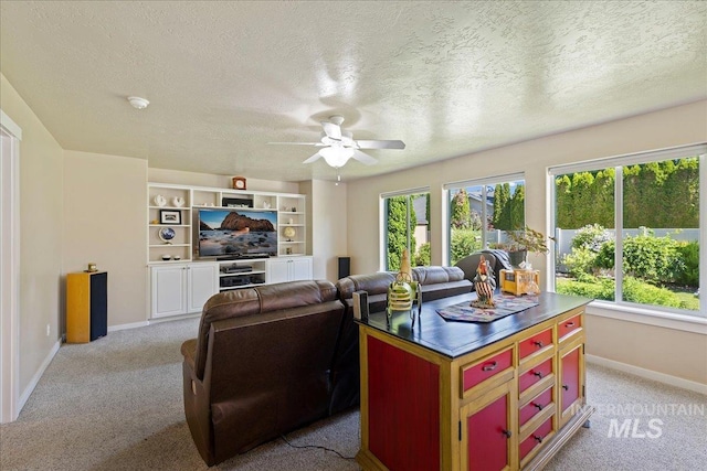 living area featuring baseboards, a textured ceiling, light colored carpet, and a healthy amount of sunlight