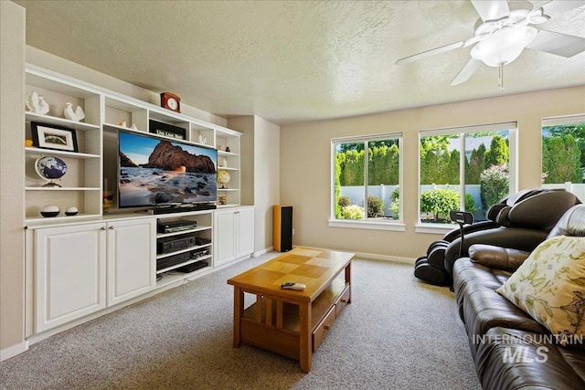 living room with carpet floors, baseboards, a ceiling fan, and a textured ceiling