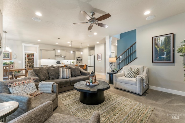 living room with decorative columns, light colored carpet, ceiling fan, and sink