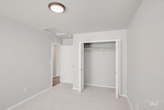 unfurnished bedroom featuring light carpet, a textured ceiling, and a closet