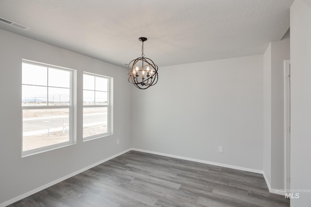 unfurnished room with a notable chandelier, wood-type flooring, and a textured ceiling