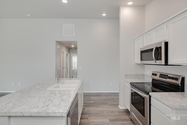 kitchen with sink, an island with sink, white cabinetry, light hardwood / wood-style floors, and stainless steel appliances