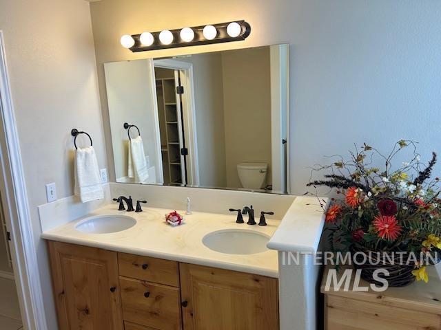 full bathroom with double vanity, toilet, and a sink