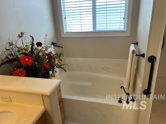 full bathroom featuring a garden tub and vanity