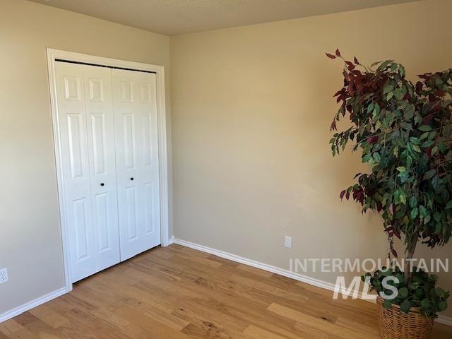 unfurnished bedroom featuring a closet, baseboards, and light wood-style floors