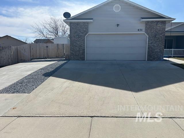 view of side of home with concrete driveway, a garage, fence, and brick siding