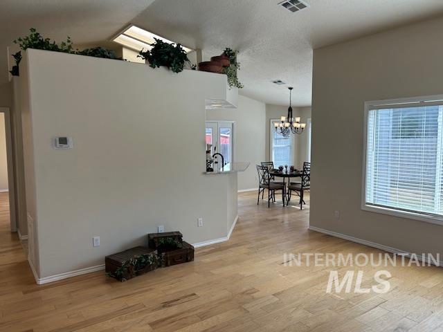 unfurnished dining area featuring a notable chandelier, wood finished floors, visible vents, and a healthy amount of sunlight