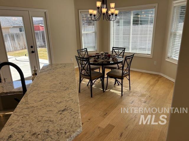 dining room featuring baseboards, light wood-type flooring, and a chandelier