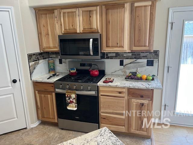 kitchen featuring decorative backsplash, light stone counters, a wealth of natural light, and stainless steel appliances