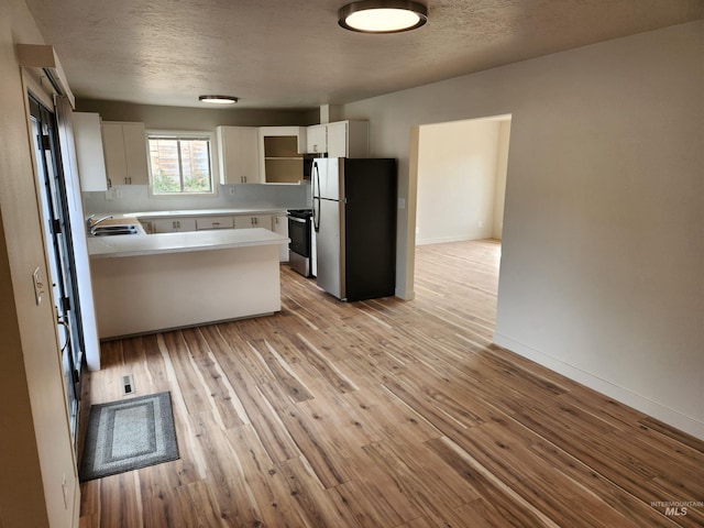 3004/3006 W Gerrard St, Boise, ID 83703 - kitchen with appliances with stainless steel finishes, light countertops, a peninsula, white cabinetry, and light wood-type flooring