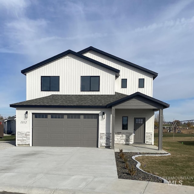 modern farmhouse featuring stone siding, concrete driveway, a front yard, a shingled roof, and a garage