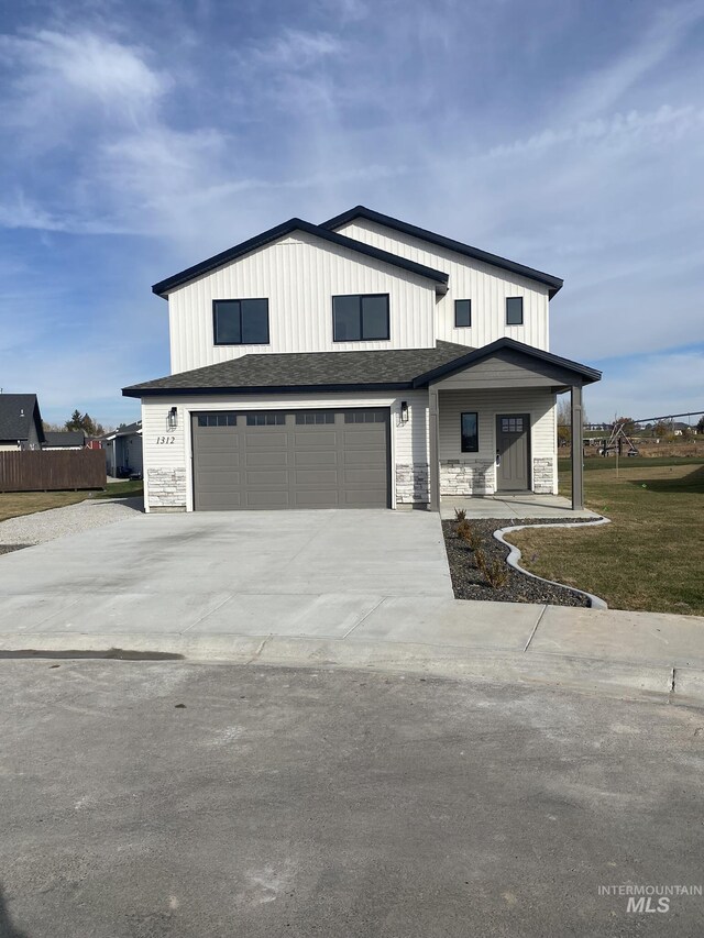 modern farmhouse with stone siding, concrete driveway, a garage, and a front yard