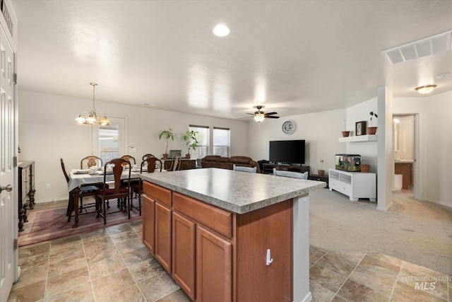 4590 E Stone Falls Dr, Nampa, ID 83686 - kitchen featuring a kitchen island, brown cabinetry, ceiling fan, a chandelier, and decorative light fixtures
