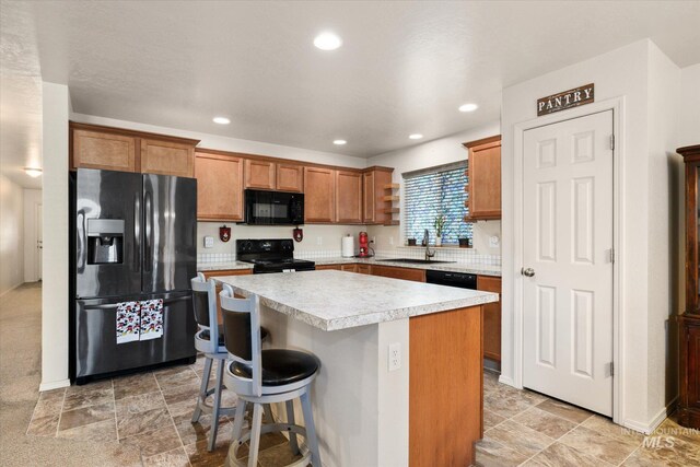 4590 E Stone Falls Dr, Nampa, ID 83686 - kitchen with black appliances, light countertops, brown cabinetry, a center island, and a kitchen bar