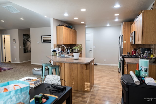 kitchen featuring sink, appliances with stainless steel finishes, decorative backsplash, and a kitchen bar