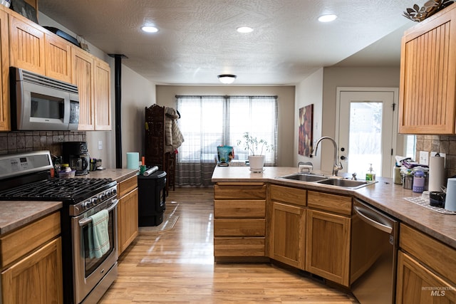 kitchen featuring stainless steel appliances, a textured ceiling, light wood-type flooring, and sink