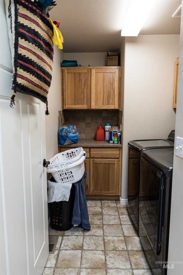 laundry area with separate washer and dryer and cabinets